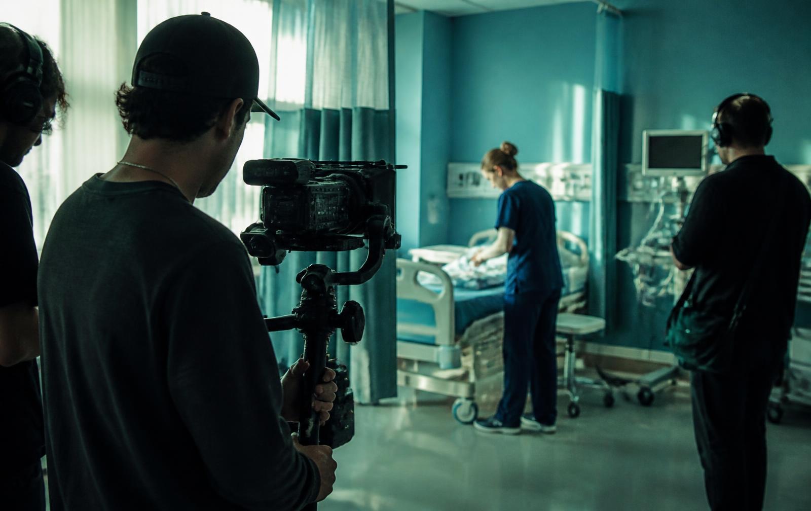A two-person film crew working quietly inside a hospital room